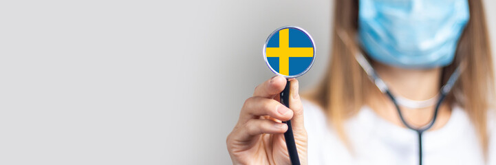 female doctor in a medical mask holds a stethoscope on a light background. Added flag of Sweden....