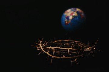 Close up of crown of thorns of Jesus over blurred world globe on black background can be used for...