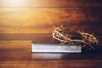 Close up of crown of thorns of Jesus on top of the holy bible on wooden table can be used for...