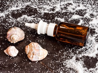 On an old, black wooden table is a brown glass bottle with saline solution for stripping the nasal...