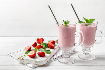 Glass of fresh strawberry and yogurt smoothie on white wooden table