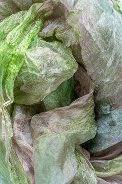Large folds of sparse Margilan silk of green, brown and white color, background texture of textiles.