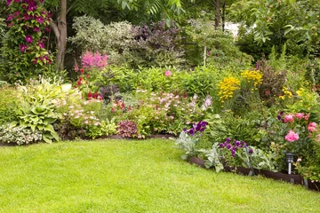 Fotobehang Beautiful colorful flower garden with blooming flower beds and a green lawn in summer © zabavna