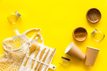 Zero waste set with recycled tableware, cotton bag, glass jars on yellow desk, top view. Plastic free, eco friendly concept