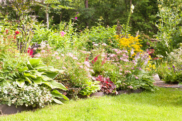 Beautiful colorful flower garden with blooming flower beds and a green grass in summer