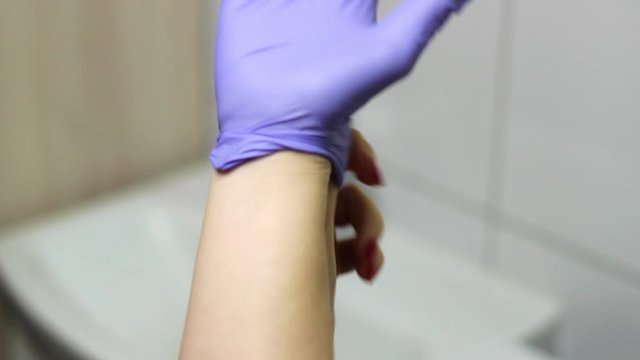 Caucasian woman puts on purple gloves to prevent coronavirus infection