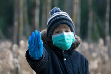 Child in protective sterile medical mask on her face looking at camera outdoors