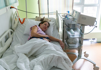 Pregnant woman feels hard contraction in a hospital labor delivery room. Concept photo of pregnancy, pregnant woman, newborn and baby.