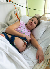 Pregnant woman feels hard contraction in a hospital labor delivery room. Concept photo of pregnancy, pregnant woman, newborn and baby.