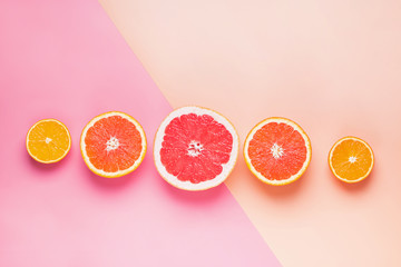 Slices of different citrus fruits on pink background