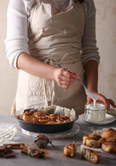 The concept of American cuisine. Pastries and desserts. Cinnabon and white glaze with hands. Buns with cinnamon and cream cheese on a light background. Background image, copy space