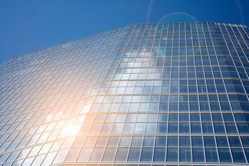 Office building glass facades on a bright sunny day with sunbeams in the blue sky. Abstract view of a skyscraper with sunlight