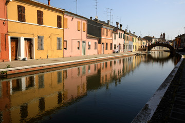 Fototapeta na wymiar Comacchio (FE), Italy - April 30, 2017: Houses in Comacchio village reflecting in the water, Delta Regional Park, Emilia Romagna, Italy