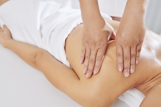 Close-up image of massage therapist applying sustained pressure using slow, deep strokes to target the inner layers of muscles