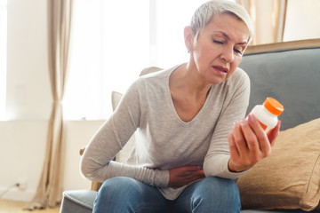 Woman with an abdominal pain sitting on the sofa