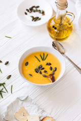 Pumpkin cream soup with cheese and onions on a white board. Still life flat lay