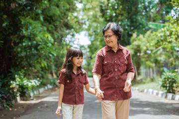 Fototapeta premium Asian grandmother with grandchildren walking together in the park enjoying a vacation