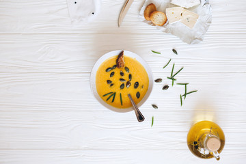 Pumpkin cream soup with cheese and onions on a white board. Still life flat lay