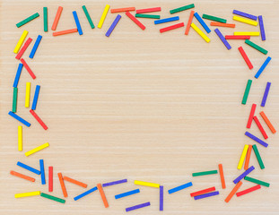 Multi-colored sticks on a wooden background. View from above. Background for text. Copy space