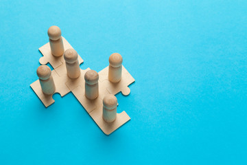 Wooden figures on puzzles on blue background as a symbol of team building. Organization group...