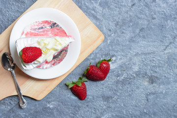 Delicious homemade strawberry cake and fresh milk cream in white dish on gray stone table rustic style. Top view with copy space.