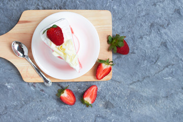 Delicious homemade strawberry cake and fresh milk cream in white dish on gray stone table rustic style. Top view with copy space.