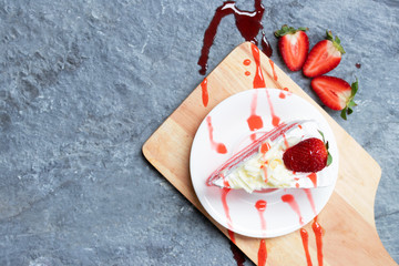 Delicious homemade strawberry cake and fresh milk cream with strawberry sauce in white dish on gray...