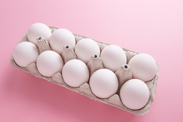 Chicken eggs in a tray close-up on a pink background.