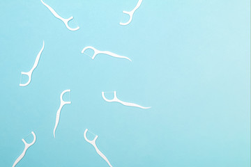 Many dental floss picks on blue color background, top view.