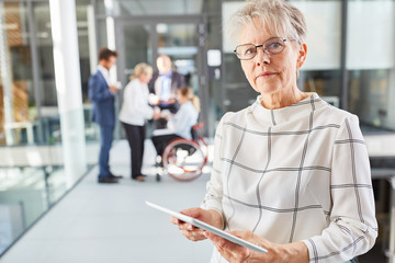 Senior woman in business company with tablet computer