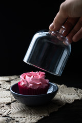 A hand opens a homemade cake covered in a vintage-style glass cap