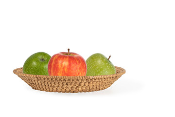 ripe red apples of different varieties in a wicker basket isolated on white background