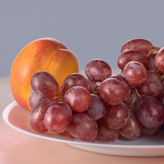 red grapes and fresh ripe fruits on a light kitchen table