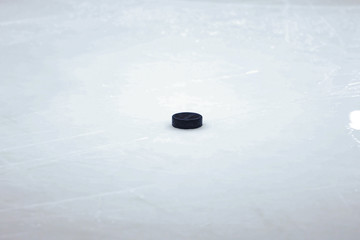 Black old ice hockey puck on ice rink.