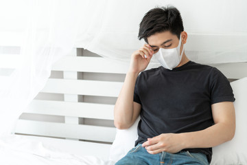 Asian man wearing Face Mask to protect  feeling sick headache and cough because of Coronavirus covid-19 in quarantine room , Quarantine yourself to protect spread Covid-19 Coronavirus