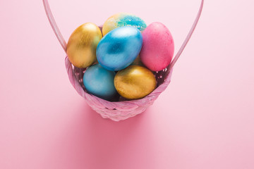 Fototapeta na wymiar Multi-colored Easter eggs in a basket on a pink isolated background. Easter is a bright holiday.