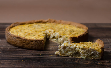 Slice of kish with caramelized onions, dill and cream cheese on a Wooden Table
