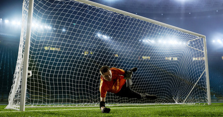 Goalkeeper is trying to save from a goal on an empty soccer stadium. No spectators on the tribunes....
