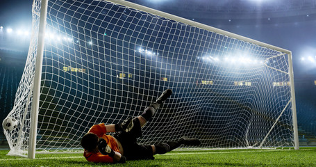 Goalkeeper is trying to save from a goal on an empty soccer stadium. No spectators on the tribunes....