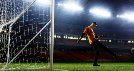 Goalkeeper kicks the ball out of the goal on the empty soccer stadium. No spectators on the tribunes. Stadium is made in 3D.