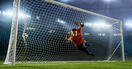 Goalkeeper is trying to save from a goal on an empty soccer stadium. No spectators on the tribunes. Stadium is made in 3d.