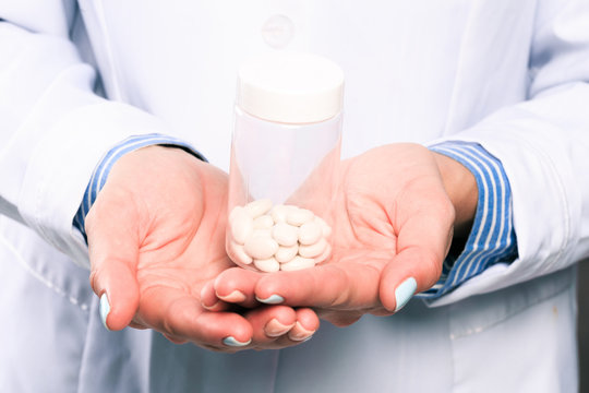 Doctor hand in sterile gloves holding jar with pills close up view  - Image