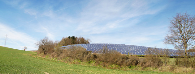 Panoramic view of solar panels in a green field , photovoltaics, alternative electricity source - concept of sustainable resources
