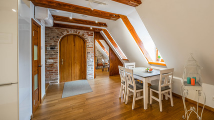 Wooden loft contemporary interior of private house. Entrance door. Sloping ceiling with windows. Fruits on the table.