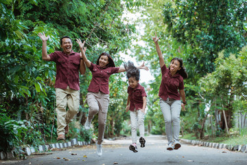 Obraz premium Happy family jumping with raised hands in park during daytime