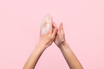 Hand washing. Soapy female hands on a pink background. Concept of the rules of washing and handling hands. Top view, flat lay