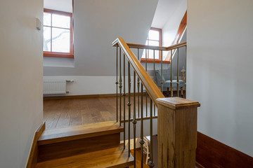 Modern loft interior of hall on the second floor in apartment. Wooden staircase.