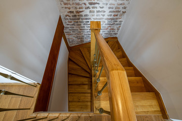 Top view of a wooden staircase and handrails. Brick wall. Loft interior of private house.