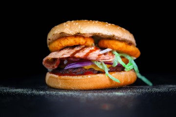 Tasty cheese burger with grilled bacon and onion rings