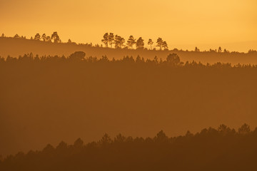 Sunset with orange sky and many layered hills